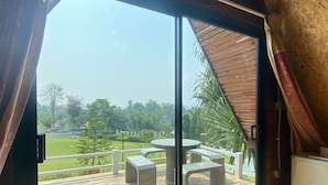 A room with a sliding glass door leading to an outdoor deck with a round table and benches. - Goodview Resort & Camping (Sai Yok)