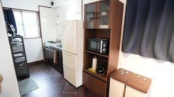 A compact kitchen with a refrigerator, microwave, and wooden cabinets.