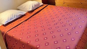 A single bed with a patterned bedspread, a headboard, and a window with a view of greenery outside. - Grand Bleu Cottage Les Pescalunes (Agde)