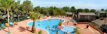 Un espace piscine comprenant plusieurs bassins, entouré de palmiers et de chaises longues.