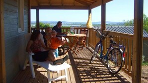 A covered outdoor seating area with a table and chairs, a bicycle, and a view of the landscape. - Grand Bleu Cottage Les Pescalunes (Agde)