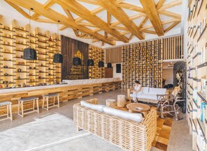 Un intérieur moderne avec des poutres en bois, un espace salon central et des étagères où sont exposés divers objets.