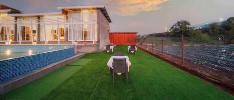 A hotel with a swimming pool, outdoor seating, and a view of the surrounding landscape.