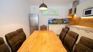 A modern kitchen with a wooden dining table, brown upholstered chairs, a stainless steel refrigerator, and a microwave. - Apartment Summer & Winter Fun I (Zell am See)