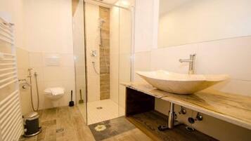 A modern bathroom with a glass-enclosed shower, a large vessel sink, and a wooden vanity.