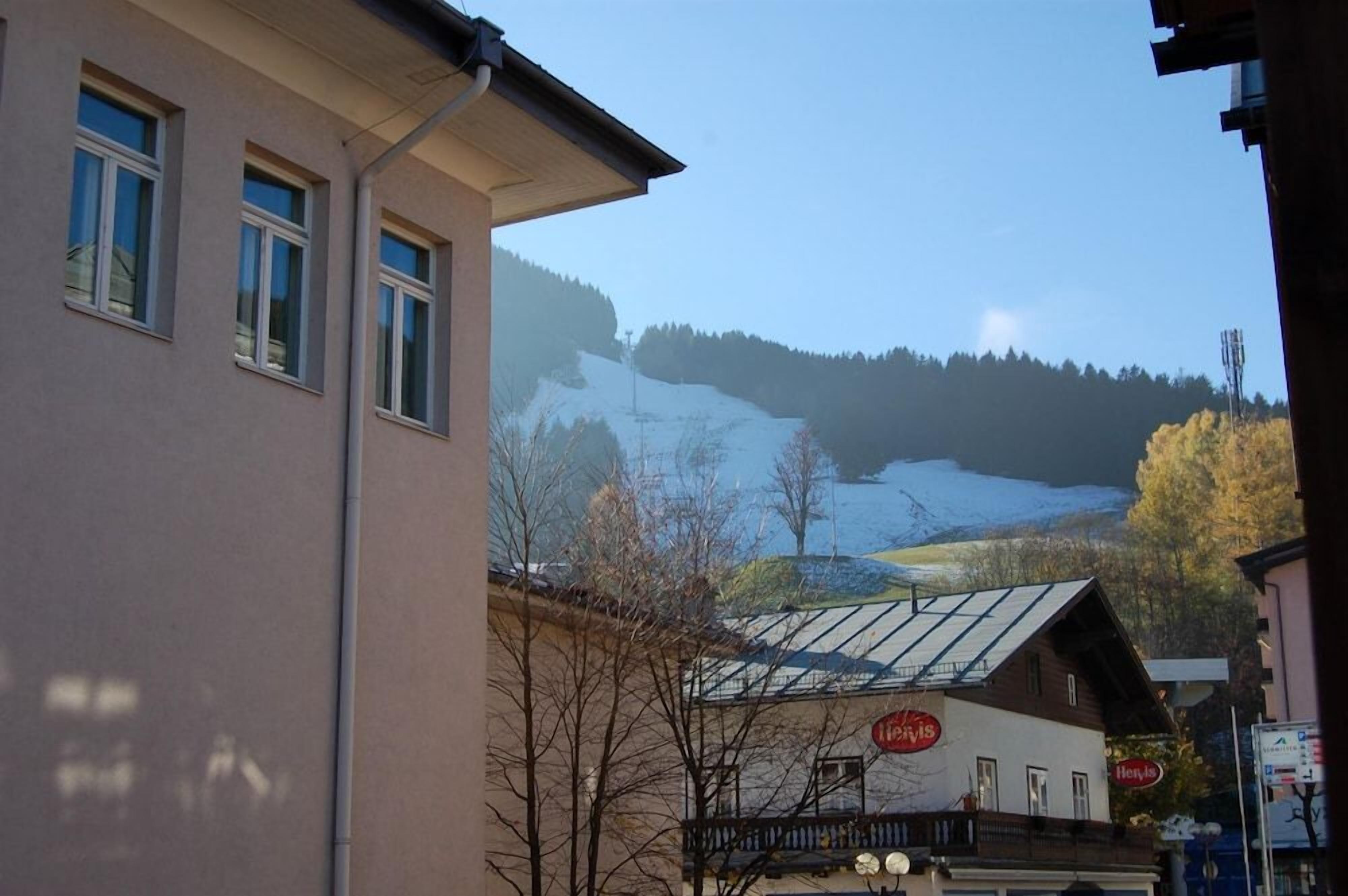 A building with a snow-covered mountain in the background, a clear sky, and a sign that reads 'Hotel'.