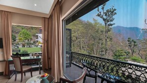 A balcony with a dining table and chairs, a view of a mountainous landscape, and a glimpse of a garden outside. - Shaantam Resorts (Yamkeshwar)