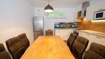 A modern kitchen with a wooden dining table and chairs, a refrigerator, and a microwave.