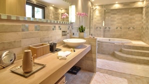 Un baño moderno con un lavamanos grande, una bañera y una zona de ducha.