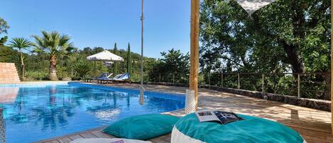 A pool area with lounge chairs and a wooden deck.