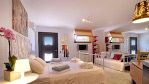 Un dormitorio bien iluminado con cama, mesitas de noche, televisor y espejo.