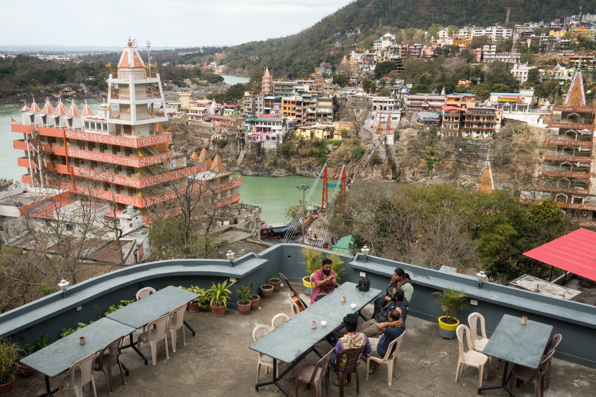 A terrace with outdoor seating and a view of a town with buildings and a river.