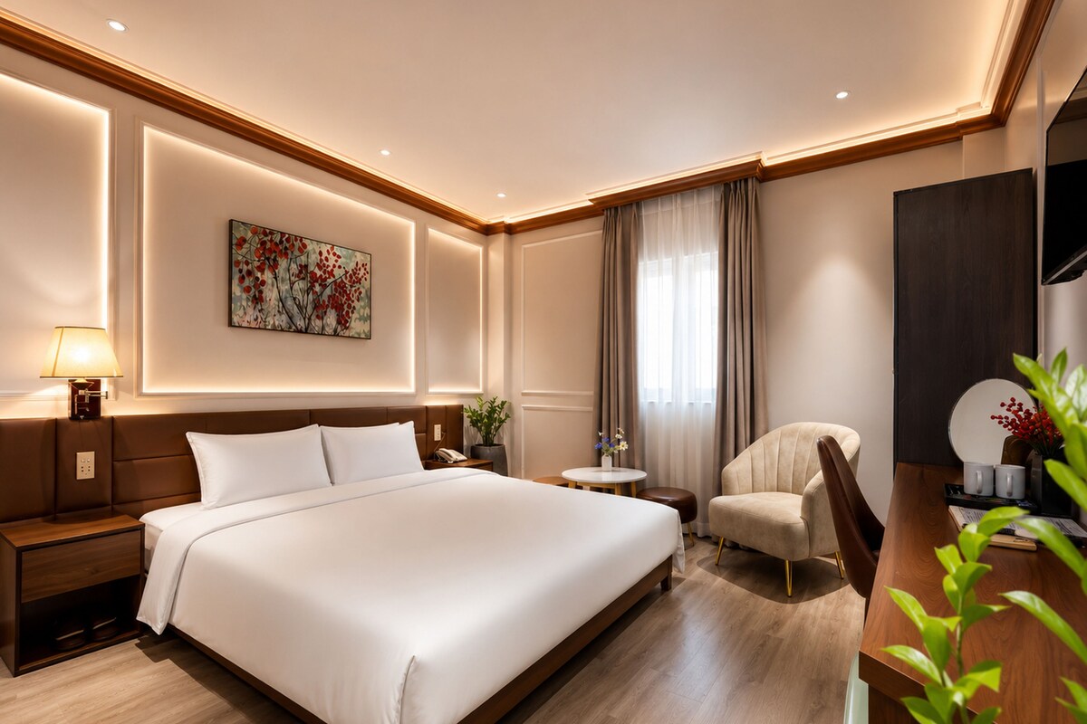 Ein Hotelzimmer mit einem großen Bett, Nachttischen, einem Schreibtisch, einem Stuhl, einer Lampe, einem Gemälde und einem Fenster mit Vorhängen.