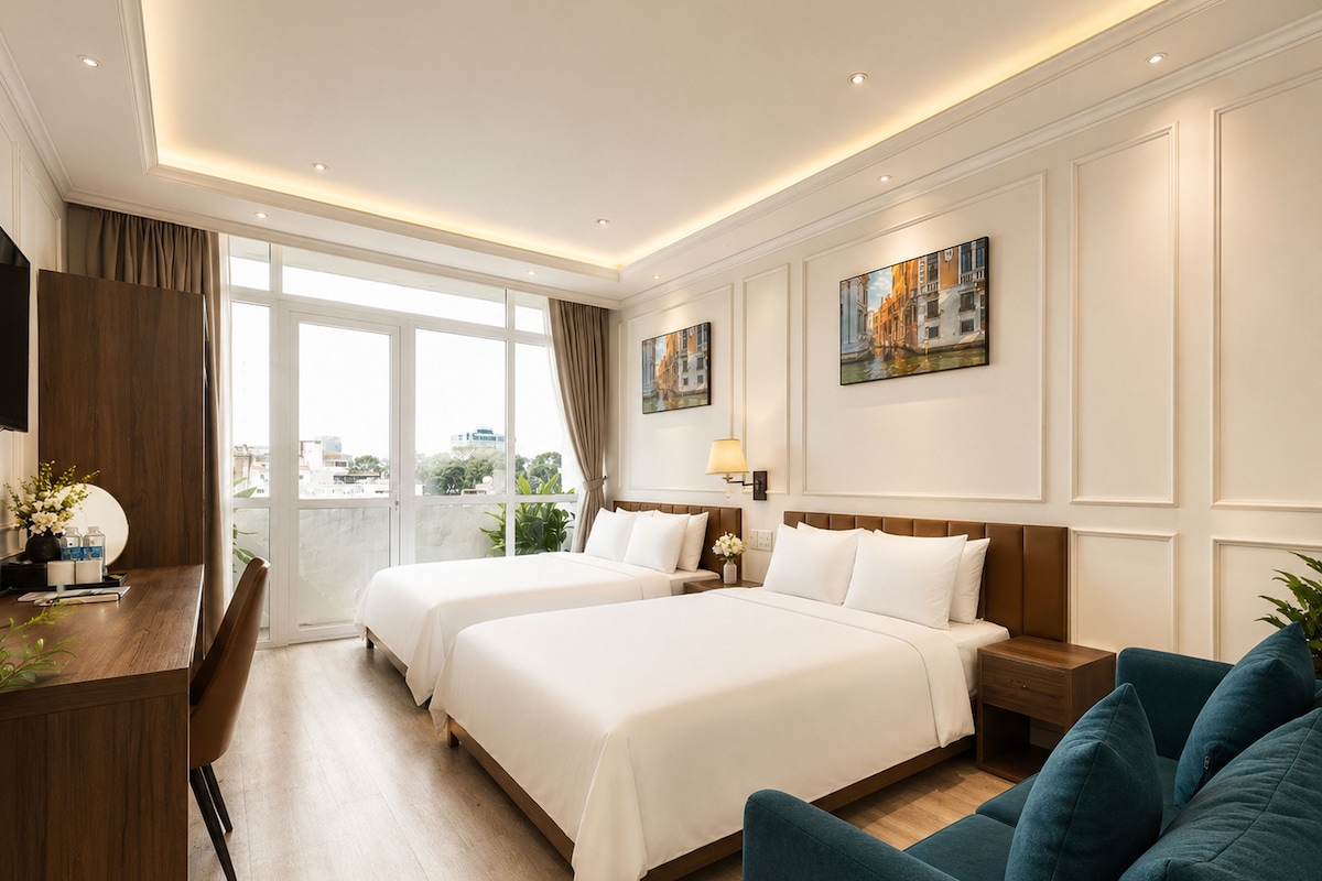 Ein Hotelzimmer mit zwei Betten, einem Schreibtisch, einer Couch und einem großen Fenster mit Blick auf die Stadt.