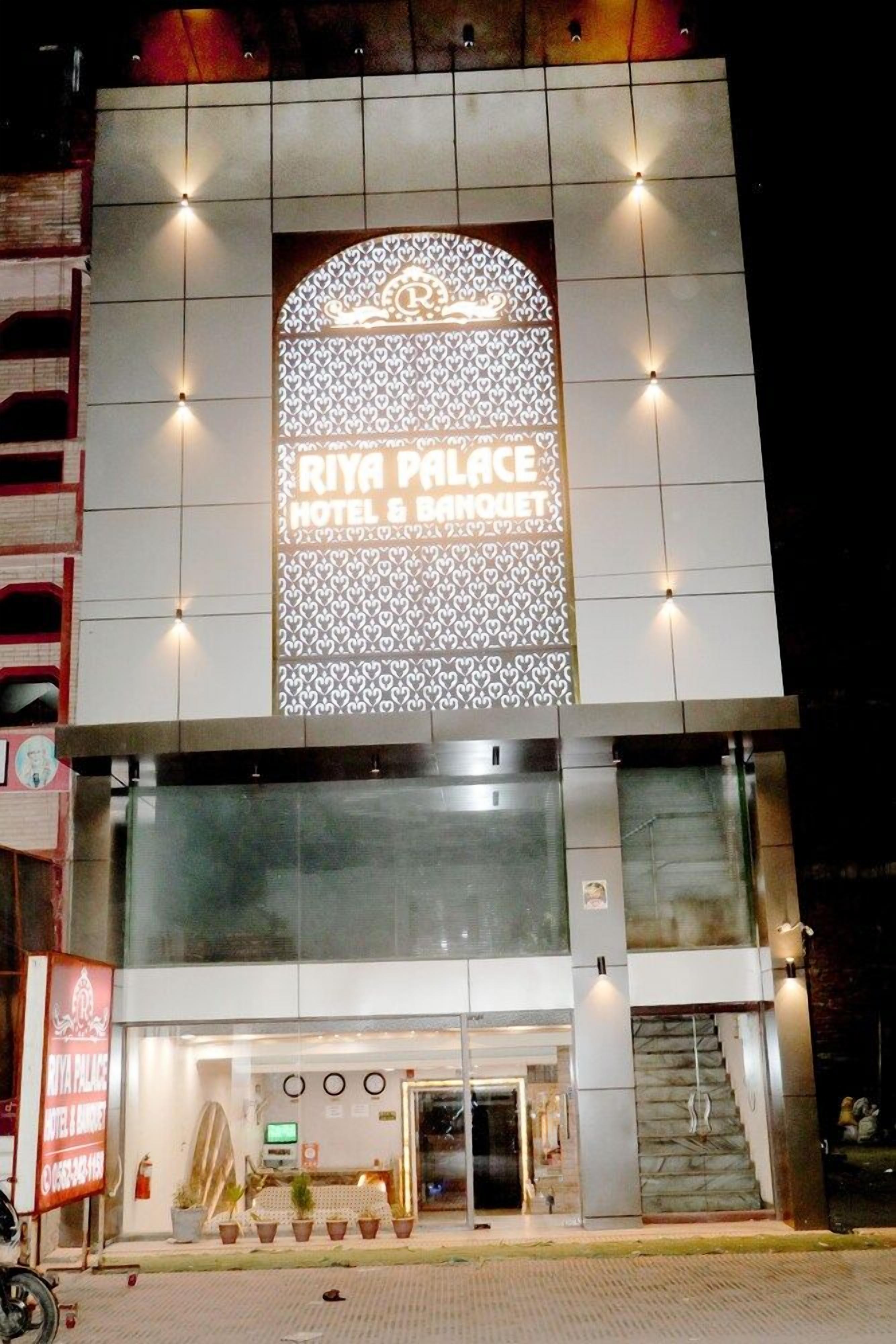 L'ingresso di un hotel con un grande cartello illuminato che riporta la scritta 'RIYA PALACE HOTEL & BANQUET'.