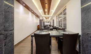 A hotel dining area with a long table, wicker chairs, and a modern ceiling design. - Treebo Sky Dale Inn & Suites (Ootacamund)