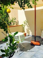 Una terrazza esterna con tavolo e sedie, piante in vaso e una pergola.