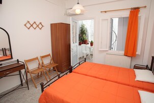 Un dormitorio con dos camas, un escritorio, sillas, un armario y una ventana con cortinas.