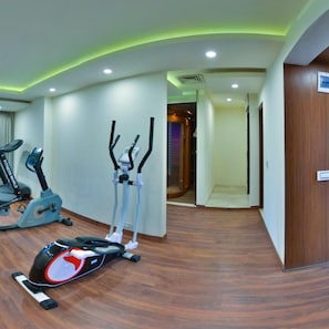 Un gimnasio de hotel con equipo de ejercicio, incluyendo una máquina elíptica, una bicicleta estática y una cinta de correr.