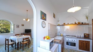 Una cocina con salpicadero de azulejos, un comedor con mesa puesta y vistas al exterior.