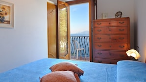 Un dormitorio con cama, cómoda y balcón con una silla.