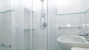 A bathroom with a glass-enclosed shower, a white sink, and a tiled floor. - Moressa Little (Praiano)