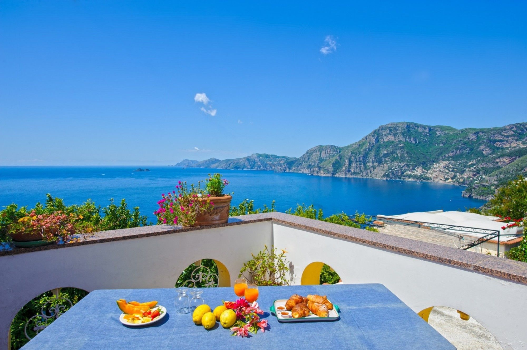 Una mesa lista para el desayuno con vistas al mar y a las montañas.