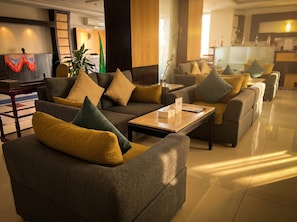 A hotel lobby with sofas and armchairs arranged in a semi-circle, a coffee table in the center, and a reception desk in the background. - Tulip Al Rawdah (Riyadh)