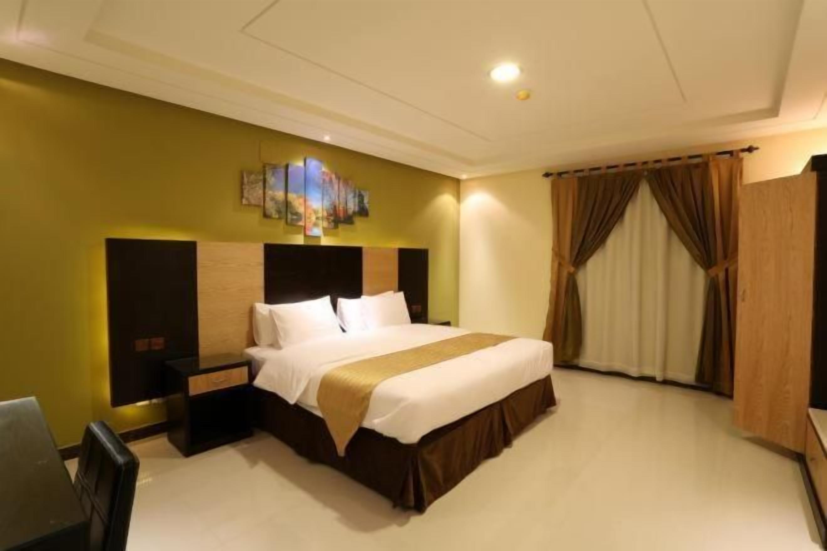 A hotel room with a large bed, a desk, and a chair.