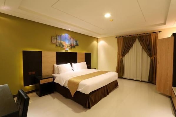 A hotel room with a large bed, a desk, and a chair. - Tulip Al Rawdah (Riyadh)
