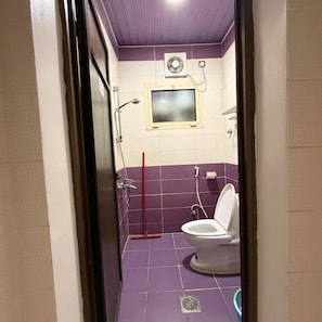 A small bathroom with a toilet, a shower, and a window. - Aros Alfaisaliah Furnished Units (Dammam)