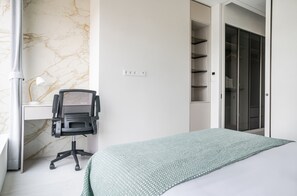 Quarto com cama, escrivaninha e cadeira.