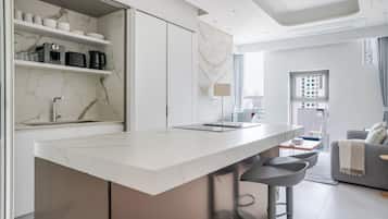 A modern kitchen with a marble countertop, built-in appliances, and a large window.
