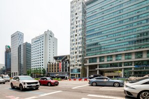 A city street with modern buildings, a crosswalk, and cars.