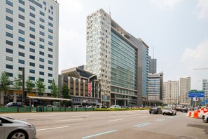 Um hotel com várias andares e fachada moderna, situado numa área urbana movimentada com outros edifícios altos por perto.