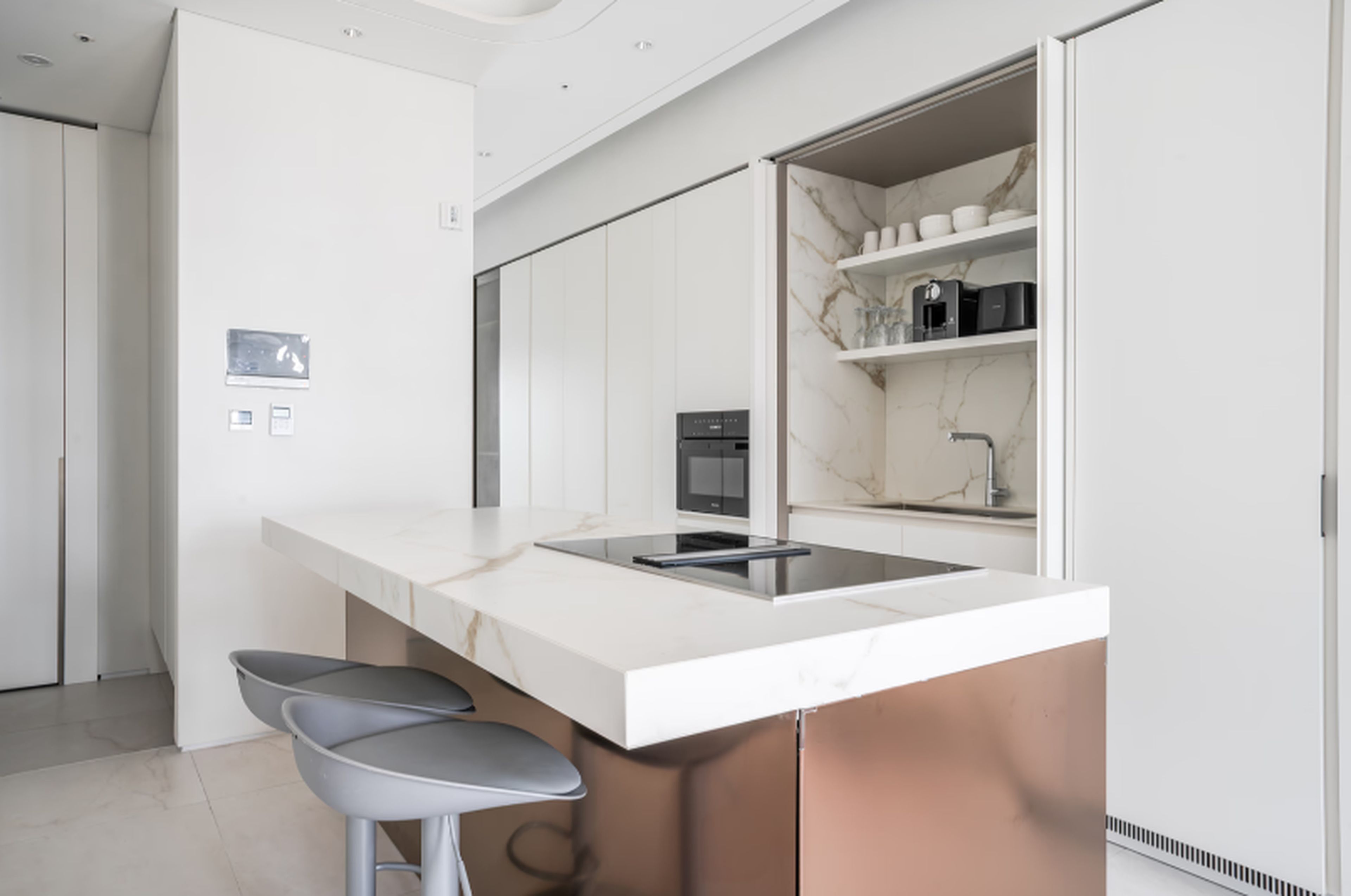 A modern kitchen with a white countertop, stainless steel appliances, and a marble backsplash.