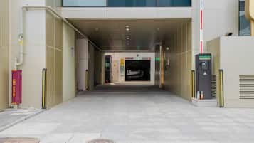 Entrada de um edifício com caminho livre até uma área de estacionamento, um hidrante e uma cabine de segurança.