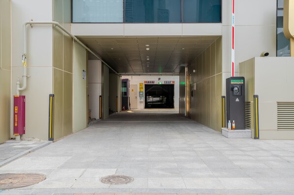 Entrada de um edifício com caminho livre até uma área de estacionamento, um hidrante e uma cabine de segurança.
