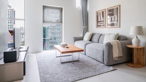 A modern living room with a grey sofa, a coffee table, and a city view through large windows. - Orchid Cheongdam - Executive Suite - 5 mins to Coex by Taxi (Seoul)