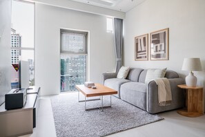 Una sala moderna con un sofá gris, una mesita de centro y vistas a la ciudad a través de amplios ventanales.