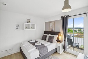 A modern bedroom with a bed, bedside table, and a view of the outdoors.