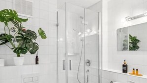 Un baño moderno con ducha de vidrio, lavamanos blanco y un inodoro.
