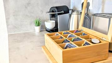 Une cuisine équipée d’une machine à café, d’un grille-pain et d’une boîte en bois à compartiments.
