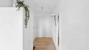 Un pasillo con suelo de madera, paredes blancas y una puerta al final.