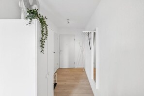 A hallway with a wooden floor, white walls, and a door at the end. - Go2Cozy - Study & Work Apartments (Kaiserslautern)
