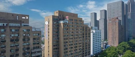 A high-rise building with multiple floors, a visible clock, and a sign indicating a hotel.