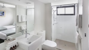 A modern bathroom with a bathtub, toilet, and shower. - Sea Breeze Mooloolaba (Sunshine Coast)