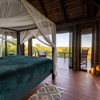 Una habitación con cama, vistas al exterior y un balcón con una silla.