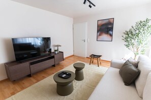 A modern living room with a flat-screen TV, a sofa, a coffee table, a small stool, and a potted plant. - 100 m² · up to 6 guests · 3 bedrooms · 8 km from Bamberg (Kemmern)