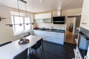 Eine moderne Küche mit weißen Schränken, einer schwarzen Arbeitsplatte und einem eingebauten Backofen.